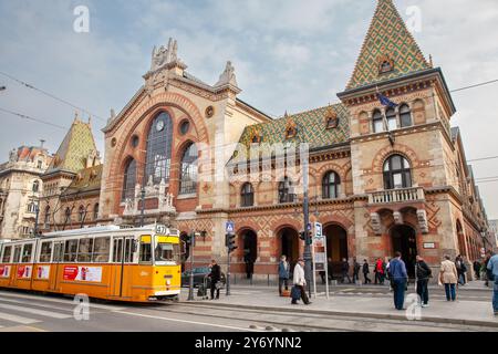 Personnes devant la Grande halle du marché à Budapest (Nagycsarnok ou Vasarcsarnok), façade extérieure du bâtiment, arrêt du tramway à l'extérieur, Budapest Hongrie Banque D'Images