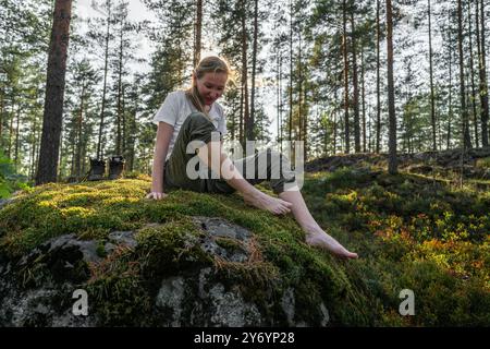 femme assise sur une pierre avec de la mousse sans chaussures dans la forêt Banque D'Images