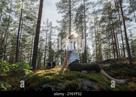 femme assise sur une pierre sans chaussures dans la forêt d'automne de la lumière du soleil Banque D'Images