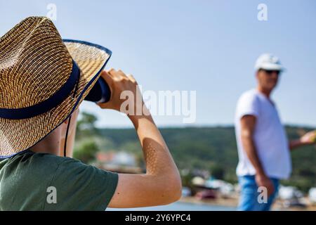 Le jeune garçon regarde son père avec des jumelles Banque D'Images