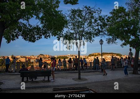 Une vue panoramique au coucher du soleil de Miradouro Sao Pedro de Alcantara d'un paysage urbain densément construit mis en évidence par le Castelo de Sao Jorge sur une colline . Banque D'Images
