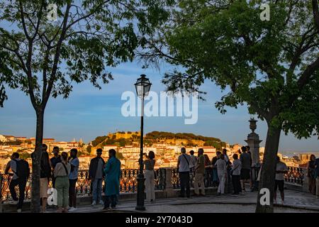Une vue panoramique au coucher du soleil de Miradouro Sao Pedro de Alcantara d'un paysage urbain densément construit mis en évidence par le Castelo de Sao Jorge sur une colline . Banque D'Images