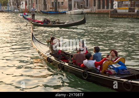 Les gondoles emmènent les touristes armés de caméras pour une promenade en fin d'après-midi le long du Grand canal à Venise Banque D'Images