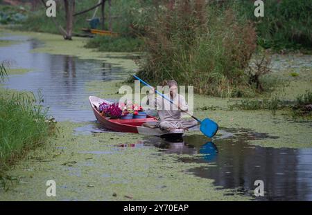 Srinagar, le Cachemire sous contrôle indien. 27 septembre 2024. Un homme rame un bateau avec des fleurs fraîches au lac Dal à Srinagar, la capitale estivale du Cachemire contrôlé par les Indiens, le 27 septembre 2024. Crédit : Javed Dar/Xinhua/Alamy Live News Banque D'Images