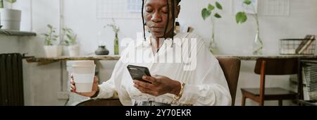 Bannière de site Web de femme d'affaires afro-américaine utilisant un smartphone pour vérifier les médias sociaux tout en ayant une pause-café Banque D'Images
