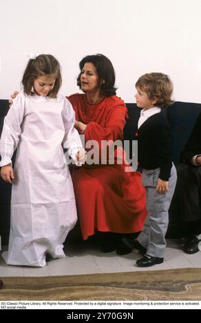 Princesse héritière Victoria de Suède 1984. Vêtu d'un costume traditionnel et de bougies lors de la célébration de la Saint-Lucy le 13 décembre. Sa mère la reine Silvia l'aide à s'habiller avec le prince Carl Philip sur le côté. Banque D'Images