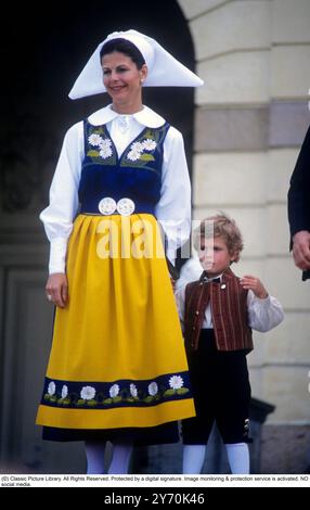 La reine Silvia de Suède vêtue d'un costume traditionnel suédois avec son fils le prince Carl Philip, assistant à la cérémonie de célébration de la fête nationale de la Suède au Musée Skansen à Stockholm le 6 juin 1984. Banque D'Images