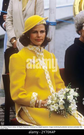 Reine Silvia de Suède photographiée dans un manteau jaune et un chapeau jaune assorti lors de la cérémonie de remise du nom du navire M / S Mälar Victoria 1984. Banque D'Images