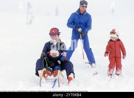 Carl XVI Gustaf, roi de Suède et ski familial 1981. Le roi Carl XVI Gustaf, la reine Silvia leurs enfants, la princesse héritière Victoria et le prince Carl Philip photographiés assis sur un traîneau et skis. Banque D'Images