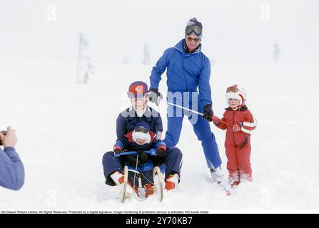 Carl XVI Gustaf, roi de Suède et ski familial 1981. Le roi Carl XVI Gustaf, la reine Silvia leurs enfants, la princesse héritière Victoria et le prince Carl Philip photographiés assis sur un traîneau et skis. Banque D'Images