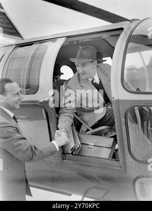 UN HÉLICOPTÈRE RELIE LONDRES ET PARIS Un hélicoptère Westland - Sikorsky a décollé du toit des garages Metropolis , adjacent à Olympia ( Londres 0 pour Paris . Ce nouveau service est conçu pour soulager les passagers aériens des problèmes de transport terminal qui surviennent lors de voyages aériens normaux. Les passagers potentiels sont capables de conduire presque jusqu'à la piste d'air du toit , de monter à bord de l'hélicoptère , et en seulement deux heures et demie se retrouvent au coeur de la capitale française . PHOTOS :- Mr . Alan Bristow , pilote de l'hélicoptère , photographié avant de décoller du toit Banque D'Images