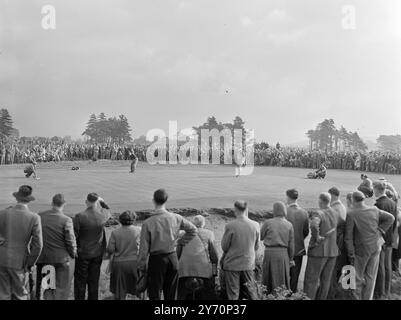 GALERY SUR LE GREEN surveillé par de grandes foules sur le second green, Max Faulkner, de Grande-Bretagne, fait un court putt dans le match d’ouverture des singles de la Ryder Cup entre la Grande-Bretagne et l’Amérique. Les adversaires de Faulkner, E.J.(Dutch) Harrison (à droite) ont coulé son tir de quatre yards pour en mener deux. Harrison, probablement le plus grand membre de l'équipe américaine, a gagné par 8 et 7, marquant la première victoire pour son pays dans une journée de golf qui a laissé la Grande-Bretagne submergée. Les Américains conservent la coupe, remportant 7 matchs à 5, malgré les débuts prometteurs de la Grande-Bretagne dans les quatre. 18 septembre 1949 Banque D'Images