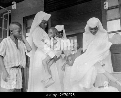 Soeurs de l'hôpital Saint Rosaire d'Emekuku dans l'État sécessionniste du Biafra, infirmières de jeunes enfants souffrant de malnutrition. Hier , Lord Hunt , héros britannique de l'Everest , et sa mission de miséricorde britannique auprès des réfugiés du Biafra , ont été refoulés à Oron , au Nigeria , par les chefs de l'armée fédérale à cause des combats sur le Rod - le front de bataille n'est qu'à 13 miles de là . Le colonel Benjamin Adekunle , Iron Man de l'armée fédérale nigériane , a accusé hier Lord Hunt et sa mission de rechercher une publicité peu coûteuse . 11 juillet 1968 Banque D'Images