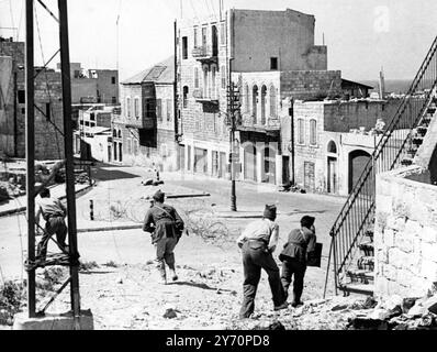 Alors que le général Alan Cunningham , haut commissaire britannique en Palestine , organisait un cessez-le-feu à Jérusalem entre Juifs et Arabes , les derniers tireurs d'élite arabes étaient libérés de leurs postes à Haïfa par des patrouilles juives . Cette photo montre une patrouille juive qui sort les derniers tireurs d'élite arabes depuis des postes de la rue Stanton, l'artère principale de Haïfa , la ville arabe récemment saisie par les Juifs . 12 mai 1948 Banque D'Images