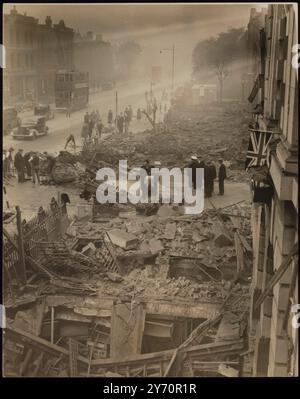 LE DRAPEAU BRITANNIQUE FLOTTE TOUJOURS COURAGEUSEMENT SUR LES RUINES DU SUD DE LONDRES CAUSÉES PAR LA BOMBE NAZIE. Lors d'un raid aérien ennemi sur la Grande-Bretagne, un avion allemand pénétra dans la région de Londres et une bombe larguée dans un quartier du sud de Londres fit un grand cratère dans le sol, démolit des magasins et des maisons d'habitation et endommagea le bâtiment des bains publics. De grands blocs d'appartements situés à une courte distance étaient intacts et les nombreuses personnes qui les occupaient habituellement étaient en sécurité dans leurs abris. PHOTO MONTRE : - L'Union Jack, symbole de la liberté de la Grande-Bretagne, toujours en vol des bâtiments publics de bains dans un quartier du sud de Londres. Note Nazi bo Banque D'Images