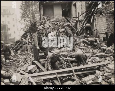 LES GARDIENS AIDENT AUX TRAVAUX DE SAUVETAGE AU CENTRE DE REPOS BOMBARDÉ. Les gardiens aident les escadrons de sauvetage des précautions aériennes à extirper les personnes enterrées par des débris lorsqu'une salle publique de Londres a été bombardée par des raids de nuit allemands. La salle était utilisée comme centre de repos pour les personnes qui avaient été bombardées hors de leurs maisons. PHOTO MONTRE : les gardes nettoyant les débris dans leurs efforts pour atteindre les personnes piégées. 17 octobre 1940 CENSEUR no 83439 Banque D'Images