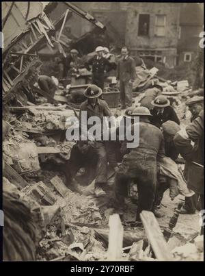 UNE MAISON PUBLIQUE TOUCHÉE PAR UNE BOMBE LORS de RAIDS NOCTURNES lors de nouveaux bombardements aveugles sur la région de Londres par des raids nocturnes allemands une maison publique a été touchée à Londres. PHOTO MONTRE : groupe de secours au travail au milieu des débris en train de porter un corps de l'épave. 19 octobre 1940 CENSEUR No 84142 Banque D'Images