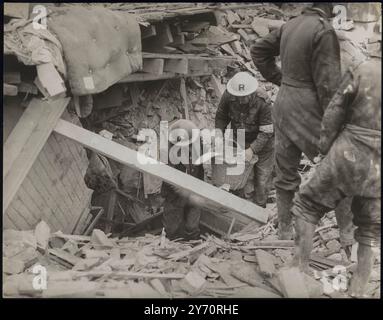 CINQ PERSONNES PIÉGÉES DANS UN SOUS-SOL EN TRAIN D'ÊTRE CREUSÉES PAR DES HOMMES DE L'A.R.P. - TOUJOURS EN VIE ET EN BONNE SANTÉ. Cinq personnes qui ont été piégées par des débris dans le sous-sol d'une maison détruite par une bombe lors des raids nocturnes dans la région de Londres sont maintenant en train d'être déterrées par des agents de précaution des raids aériens. Les gens sont vivants et pensés pour être bien. LA PHOTO MONTRE:- les membres d'une escouade de réparation A.R.P. utilisant un panier pour enlever les débris. 10 septembre 1940 CENSEUR No 68212 Banque D'Images