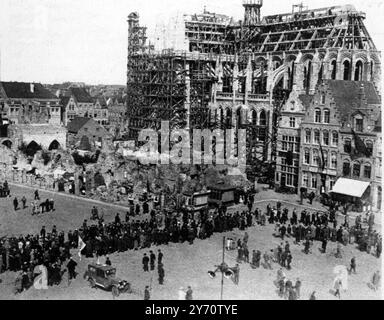 La défense immortelle d'Ypres saillant : le mémorial de la porte de Menin , symbole de courage et d'endurance . En passant par les ruines de la salle des étoffes (à gauche) et la cathédrale reconstruite : ' pèlerins ' à Ypres en route pour le dévoilement du mémorial de la porte de Menin . 24 juillet 1927 Banque D'Images