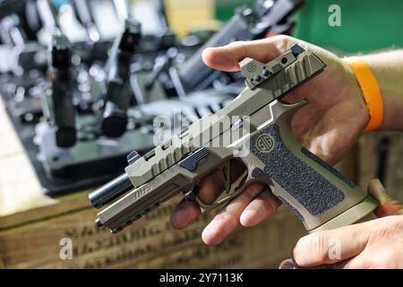 Leipzig, Allemagne. 27 septembre 2024. Un homme montre un pistolet SIG Sauer P320 DH3 sur le stand d'un marchand d'armes de chasse au salon Jagd & Angeln 2024 à Agra. Du 27 au 29 septembre 2024, environ 250 exposants présenteront tout pour les chasseurs et les pêcheurs. En plus d'une large gamme d'armes, d'optiques et d'équipements, il y aura également de nombreuses démonstrations telles que des spectacles aériens, des exercices de tir et des chevaux de dos. Crédit : Jan Woitas/dpa/Alamy Live News Banque D'Images