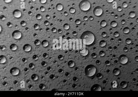 Vue de dessus des gouttelettes d'eau de pluie sur fond de couverture noir. Concept de gouttelettes d'eau Banque D'Images