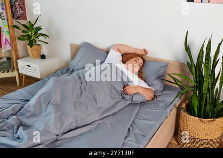 Une belle femme grande taille repose paisiblement dans sa chambre sereine ornée de plantes. Banque D'Images