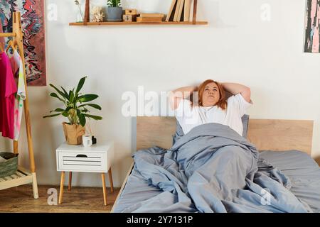 Une femme grande taille se repose dans le lit, profitant d'une matinée paisible tout en étant entourée d'un décor confortable. Banque D'Images