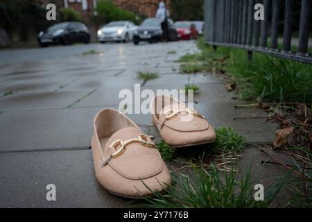 Une paire de chaussures à enfiler pour femme est vue sous des garde-corps de parc, laissée derrière peut-être par quelqu'un qui a changé ses chaussures, le 27 septembre 2024, à Londres, en Angleterre. Banque D'Images