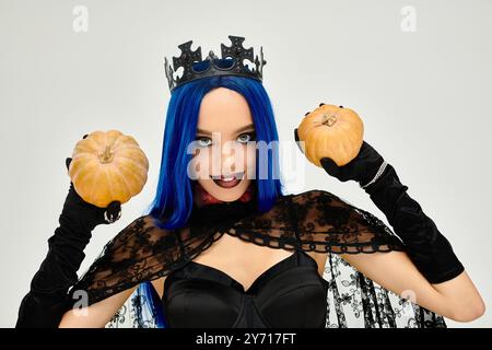 Une belle jeune dame vêtue d'un costume d'Halloween tient deux citrouilles, exsudant le charme festif. Banque D'Images