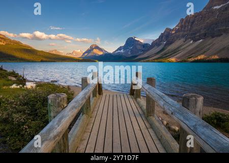 Quai en bois s'étendant vers un beau lac bleu et des montagnes par une journée ensoleillée Banque D'Images