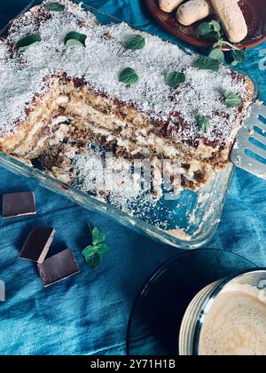 Tiramisu italien. Tiramisu au café classique avec noix de coco, chocolat, coccinelles et crème de mascarpone sur fond bleu. Directement au-dessus. Banque D'Images