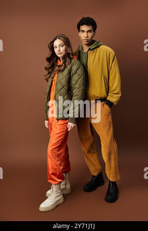 Un couple à la mode affiche en toute confiance une tenue d'automne dans des couleurs chaudes et terreuses, incarnant le style. Banque D'Images