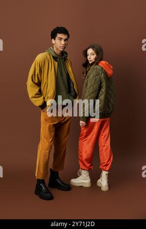 Un couple à la mode présente des tenues d'automne vibrantes, dégageant un charme douillet dans un cadre chaleureux. Banque D'Images