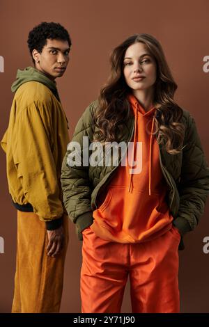 Un jeune couple à la mode présente leurs tenues d'automne, rayonnant ensemble une énergie élégante. Banque D'Images