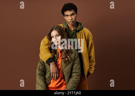 Un couple à la mode présente leur élégante tenue d'automne sur un fond riche et terreux. Banque D'Images