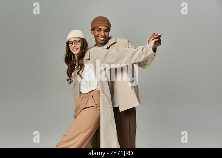 Un couple élégant affiche joyeusement leurs tenues d'automne vibrantes tout en embrassant dans un espace confortable. Banque D'Images