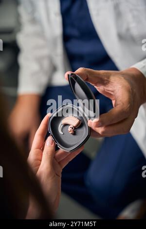 Médecin caucasien tenant un étui de prothèse auditive pour patient Banque D'Images