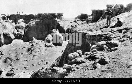A travers le désert de Gobi à un grand incubateur de dinosaures : voitures et chameaux en trek à Flaming Cliffs , Mongolie . Vu ici où le nid de quatorze oeufs avait été trouvé ' sur le bord même du bassin avec une chute pure de 200 pieds en dessous ' : Walter Granger et son assistant chinois engagés dans la tâche délicate et dangereuse de retirer les oeufs . 9 janvier 1926 Banque D'Images