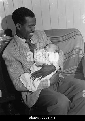 Fille de 'Junior Event' pour 'Mac' Bailey. Champion de sprint E. McDonald Bailey , est aussi heureux que s'il avait déjà remporté un titre olympique maintenant qu'il est le père fier d'une petite fille en bonne santé. Maintenant âgé de trois semaines , le bébé s'appelle Christine Elizabeth Anne et ' Mac ' espère qu'elle sera un jour championne de sprinteuse . Bailey a épousé sa femme de 21 ans il y a deux ans. Elle est Doris Wells , une fille londonienne. Spectacles d'images - ' Int première place Sprinter E. McDonald Bailey , tient bébé Christine à sa maison de Londres . 23 juin 1948 Banque D'Images