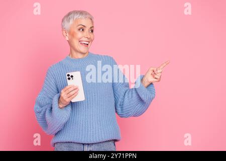 Photo de belle femme retraitée look point vide dispositif de maintien d'espace habillé élégant vêtement de tricot bleu isolé sur fond de couleur rose Banque D'Images