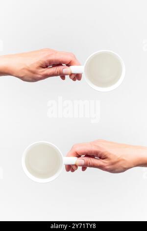 Une tasse vide en céramique blanche dans une main féminine sur un fond blanc, maquette de nourriture, vue de dessus Banque D'Images