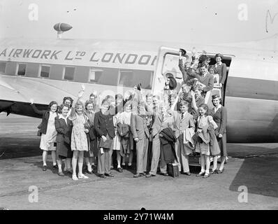 Les enfants volent sur African Holiday. Vingt-sept enfants, accompagnés de deux hôtesses de l’air, sont partis par avion de l’aéroport de Blackbushe pour passer leurs vacances d’été en Afrique de l’est où se trouvent leurs maisons. C'est le premier de trois chargements de quatre-vingt-un gamins. Un programme similaire sera mis en place à Noël, alors qu'au lieu de « Holiday Express », il sera appelé « Yuletide Express ». Photos : 'Holiday Bound' - avec des visages souriants à la pensée des vacances devant eux, ces gamins ont posé avec les deux hôtesses en charge d'eux, avant de partir dans un avion Vickers Viking pour l'Afrique de l'est. Banque D'Images