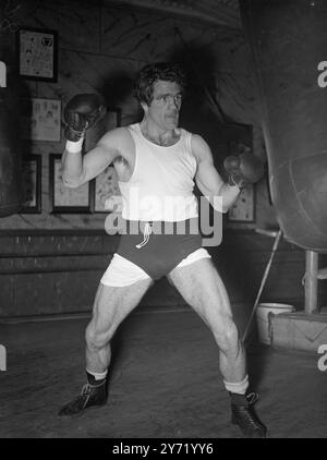 FREDDIE SE MET À L'ÉCOUTE. FREDDIE MILLS, champion du monde de poids de croiseur, se met en place un spot de formation sur le punch bag dans un gymnase du West-End pour son combat avec Johnny Ralph à Johannesburg, en Afrique du Sud, le 6 novembre. 24 septembre 1948 Banque D'Images