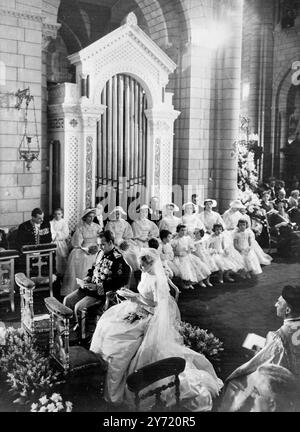 Rainier et Grace dans un moment solennel Monaco : le Prince Rainier III et son épouse Grace Kelly, sont assis solennellement dans la cathédrale Saint-Nicolas lors de leur cérémonie religieuse du mariage, qui a été conduite par Mgr Gilles Barthe. Le prince porte un uniforme orné de nombreuses commandes et décorations. Le couple Royal sera en lune de miel en Méditerranée sur le Royal Yacht. Banque D'Images