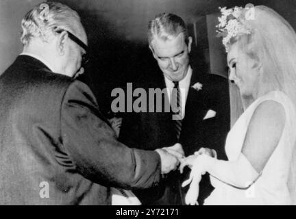 L'actrice Zsa Zsa Gabor obtient la cinquième bague de mariage de sa carrière glissée sur son doigt par le riche pétrolier texan Joshua S Cosden . Le juge Edward R Brand (à gauche) a officié lors de la cérémonie de mariage au domicile de Mlle Gabor. Miss Gabor a divorcé la semaine dernière de son quatrième mari Herbert Hutner. 10 mars 1966 Banque D'Images