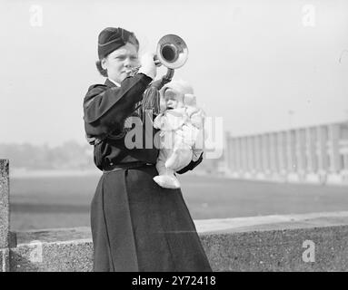 Bébé mélancolique. Bien que Mme Daphne Farrant d'Alperton, âgée de dix-neuf ans, ne soit pas « tout le temps bousculée », elle amène toujours Alan, son fils, bébé de trois mois, aux répétitions. Elle est bugler solo de l'unité d'assemblage No.7, du Girls Training corps, et s'entraîne pour le concours de Wembley Rally en juin. Images : Baby Alan prend une mauvaise vue de sa mère musicale Bugle alors qu'il pleure les mains sur ses oreilles, pendant la répétition à Wembley Today (dimanche). 7 mars 1948. Banque D'Images