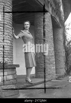 Patricia Roc, star de Gainsborough, apparaît comme une fille de travail dans son dernier film "When the Bough Breaks". Elle est vue portant un costume deux pièces en coton rouge à motifs avec motifss blanc de trèfle. Il y a quatre plis placés à l'avant de la jupe et deux grandes poches plaquées sur le manteau. La tenue a des manches courtes et une ceinture auto. 7 mai 1947 Banque D'Images