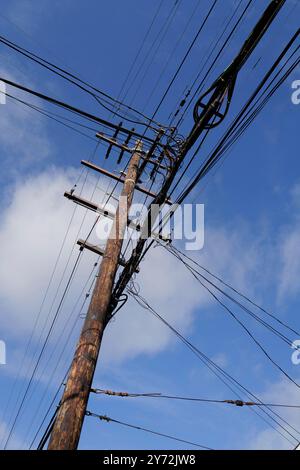 : Photos montrant des lignes électriques, des coins de rue et des voitures avec un ciel bleu clair et une infrastructure urbaine en arrière-plan. Banque D'Images