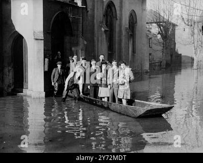 Parce que la place entourant l'église St Mary de Lode, Gloucester a été inondée par endroits, à une profondeur de 4 pieds, une fête nuptiale a dû ramer dans l'eau après le mariage là-bas hier. La mariée, Mlle Joan Bayley, et d'être transportée à l'église avant la cérémonie car aucun bateau n'a pu être trouvé. Images : la mariée et le marié quittent l'église en bateau. 21 mars 1947 Banque D'Images