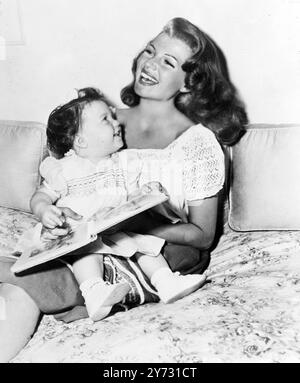 Rita et Rebecca. Par courrier aérien d'Hollywood vient cette charmante photo de Rita hayworth avec sa fille de 18 mois Rebecca (Welles). Rebecca est plus intéressée par sa mère réalisatrice de photos que par son livre d'histoires d'images. Le nouveau tableau de Rita a Columbia production est 'Down to Earth', une fascinante romance Technicolore du danseur Terpsichore. 24 juillet 1946 Banque D'Images